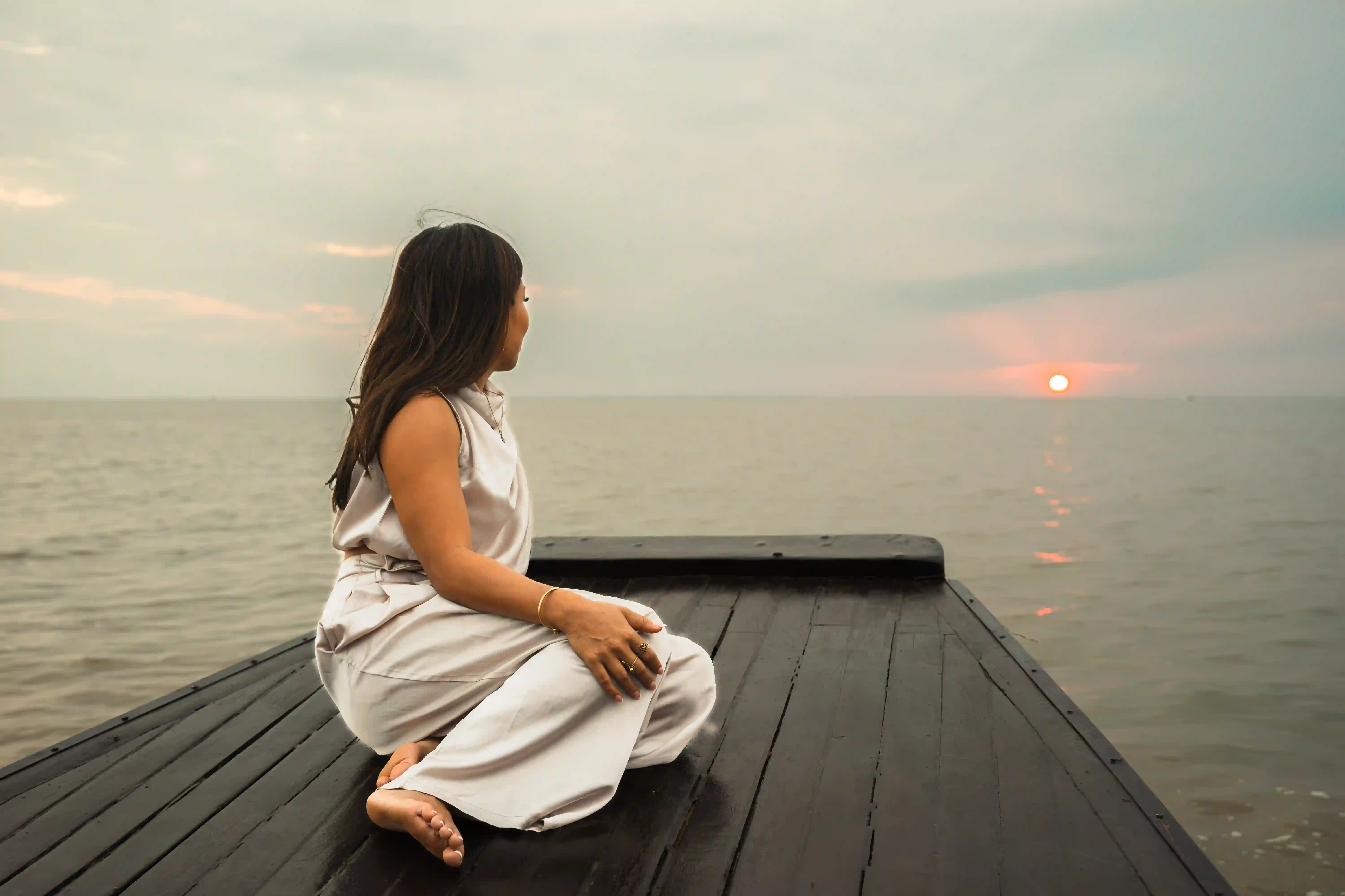Woman meditating on a wooden deck overlooking a misty mountain valley at sunrise